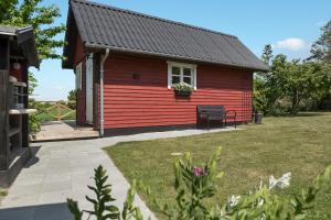 una casa rossa con una panchina nel cortile di Ølholm Cottage a Stege