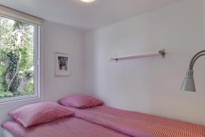 Bett in einem weißen Zimmer mit Fenster in der Unterkunft Ølholm Cottage in Stege