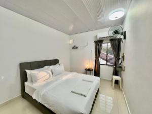 una camera da letto con un letto bianco e una finestra di Spacious 2 Storey Homestay Tanjung Bungah 25Pax by 3C a Tanjung Bungah
