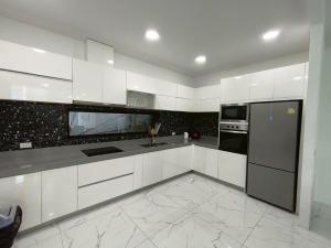 a kitchen with white cabinets and black appliances at TYb04 芭提雅北歐風格四臥室別墅 in Pattaya South