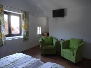 a bedroom with two green chairs and a television at Haus Steinbrecher Hallstatt in Hallstatt