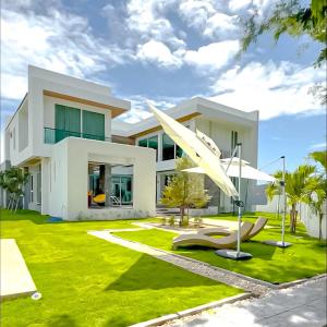 a house with a green lawn in front of it at De Flourishing Hill Pool Villa , Cha Am in Cha Am