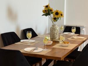 a wooden table with glasses and a vase of flowers at Zeusbnb Penthouse Sea View in Thessaloniki