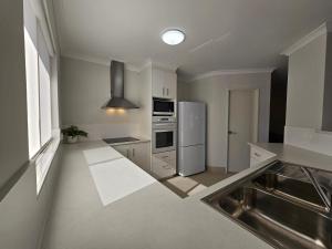 a kitchen with a sink and a refrigerator at Pelican Shore Villa 12 - Kalbarri WA in Kalbarri