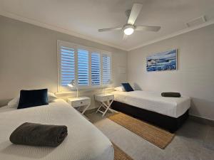 カルバリにあるPelican Shore Villa 1- Kalbarri WAのベッド2台と天井ファン付きの寝室 +4枚の写真
