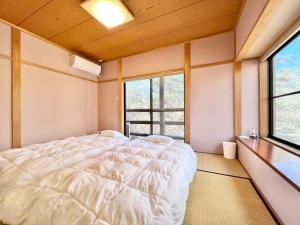 a bedroom with a large bed and two windows at 花の街589# Nature Escape BBQ in Tsumagoi