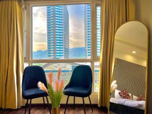 イスラマバードにあるElysium Sky-High Executive Apartments Luxury Stay Facing Centaurus Mall Islamabadの青い椅子2脚と大きな窓が備わる客室です。