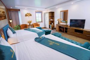 Una sala de estar con dos camas y un televisor de pantalla plana. en Crystal Holiday Ha Long Hotel, en Ha Long