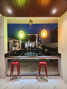 two red stools in front of a swimming pool at Bali Thousand Island Living in Pesanggaran
