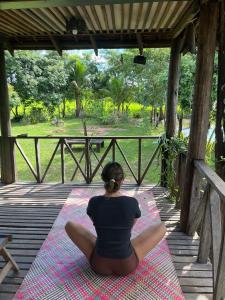 a woman is sitting on a mat on a porch at Chanmolfarmstay in Phumĭ Chŭb Chănt Sâr