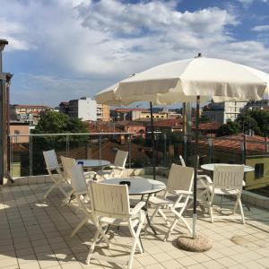 eine Terrasse mit einem Tisch, Stühlen und einem Sonnenschirm in der Unterkunft Hotel Athena in Pesaro