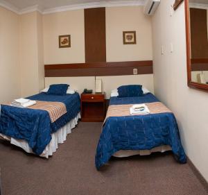 two beds in a hotel room with blue comforters at Hotel Shauard in Salta