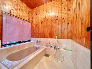 a bathroom with a tub and a wooden wall at 花の街1079# Nature Escape BBQ in Tsumagoi +28 photos