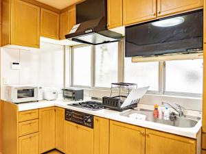 a kitchen with wooden cabinets and a laptop on the counter at The M OTAMACHI in Nakatsugawa