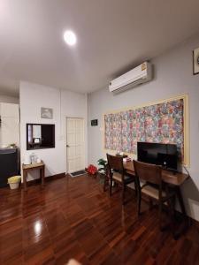 a living room with a table and chairs and a fan at INCM Guesthouse in Chiang Mai