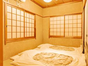 a bed in a room with two windows at The M OTAMACHI in Nakatsugawa +22 photos