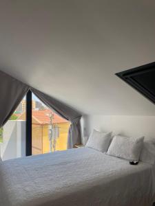 a bedroom with a white bed with a large window at Apartamento Centola julio y agost min 7N in Cangas de Morrazo
