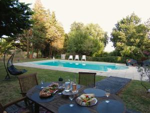 a table with food on it next to a pool at - Ancien Chai 6 pers - Vignobles - Nature - Piscine - Les hauts de la Rameyo - in Gaillac