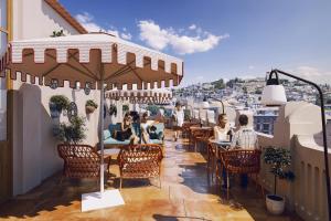a group of people sitting at tables on a balcony at The Central House Granada Elvira in Granada