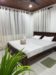 un letto in una stanza con tende bianche e piante di Cealora Resort a Dambulla