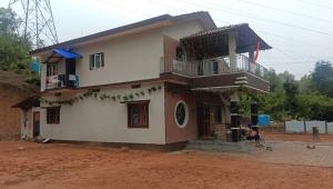 a house with a woman standing in front of it at Saketa Homestay in Linganamakki