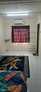 a room with a bed and a window with a rug at Alfian Homestay in Johor Bahru +1 photo