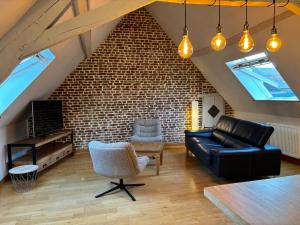 a living room with a couch and a brick wall at Côté Gîtes Cassel in Cassel