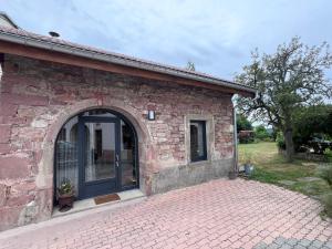 a brick building with a large glass door at Gîte de la Vologne in La Neuveville-devant-Lépanges