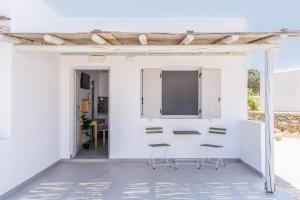 a white kitchen with chairs and a counter at Harokopou Studios in Koufonisia