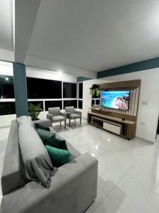 a living room with a couch and a flat screen tv at Summer Apartment in Porto De Galinhas