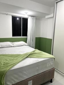a bedroom with a bed with green and white walls at Summer Apartment in Porto De Galinhas