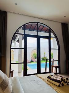 a bedroom with a large window with a view of a pool at Whãnau villa 1 in Cemagi +2 photos