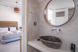 a bathroom with a sink and a mirror and a bed at Harokopou Studios in Koufonisia +85 photos