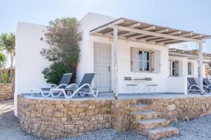 a white house with a stone wall and chairs at Harokopou Studios in Koufonisia