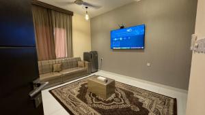 a living room with a couch and a tv on the wall at Bait Al Hakem Guest Rooms in Salalah