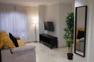 un salon avec un canapé, une télévision et un miroir dans l'établissement Hotel Bienvenidos Rooms Xàtiva, à Xàtiva