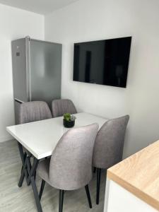 a white table with chairs and a television on a wall at Mangalia Cozy Suite in Mangalia