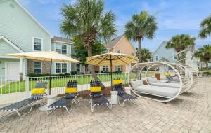 Un patio con columpio, sillas y sombrillas. en 3 Bedroom Luxury Condo with Resort Pool, Game Room, and Gym, en Panama City Beach