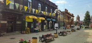 eine Stadtstraße mit Bänken, Sonnenschirmen und Gebäuden in der Unterkunft Old Avenue Hotel in Gjumri