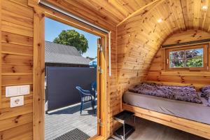 a bedroom in a wooden cabin with a large window at Campingpod Auf Der Alpakawiese in Arnsberg