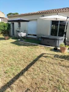Un patio con una casa con una sombrilla y una silla. en L infiniment zen, en Caromb