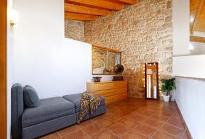 Espacioso pajar con chimenea y BBQ en el Matarraña في Lledó: غرفة معيشة مع أريكة وجدار حجري