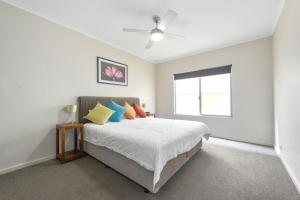 ein weißes Schlafzimmer mit einem Bett mit bunten Kissen in der Unterkunft The Cove in Port Hughes