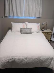 a white bed with a pillow and a window at Private SweetSuite 1 Bdrm Bathroom mini-kitchen in Kamloops +15 photos