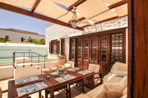 eine Terrasse mit einem Tisch, Stühlen und einem Pool in der Unterkunft Villa Andreas in Hydra