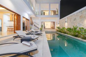 a pool with chaise lounge chairs and a swimming pool at Cosy and Luxurious Villa Sentosa Seminyak in Seminyak