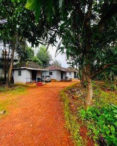 a house with a tree and a dirt road at Swarnagandha Cottages and Family rooms in Gokarna