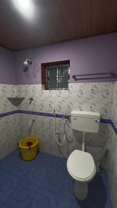 a bathroom with a toilet and a window at Swarnagandha Cottages and Family rooms in Gokarna