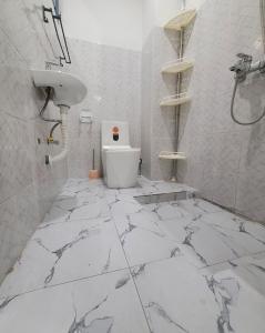 a white bathroom with a toilet and a sink at Appartement Amani in Kinshasa