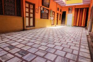马图拉Mathura Hotel Laxmi Bhawan Dharamshala Near Dwarkadhish Temple & Saryu River -Fully Air Conditioning -Free Wi-Fi -Restaurant -Parking -Room Service -Best Hotel In Mathura的一栋橙色建筑的空荡走廊，铺着瓷砖地板